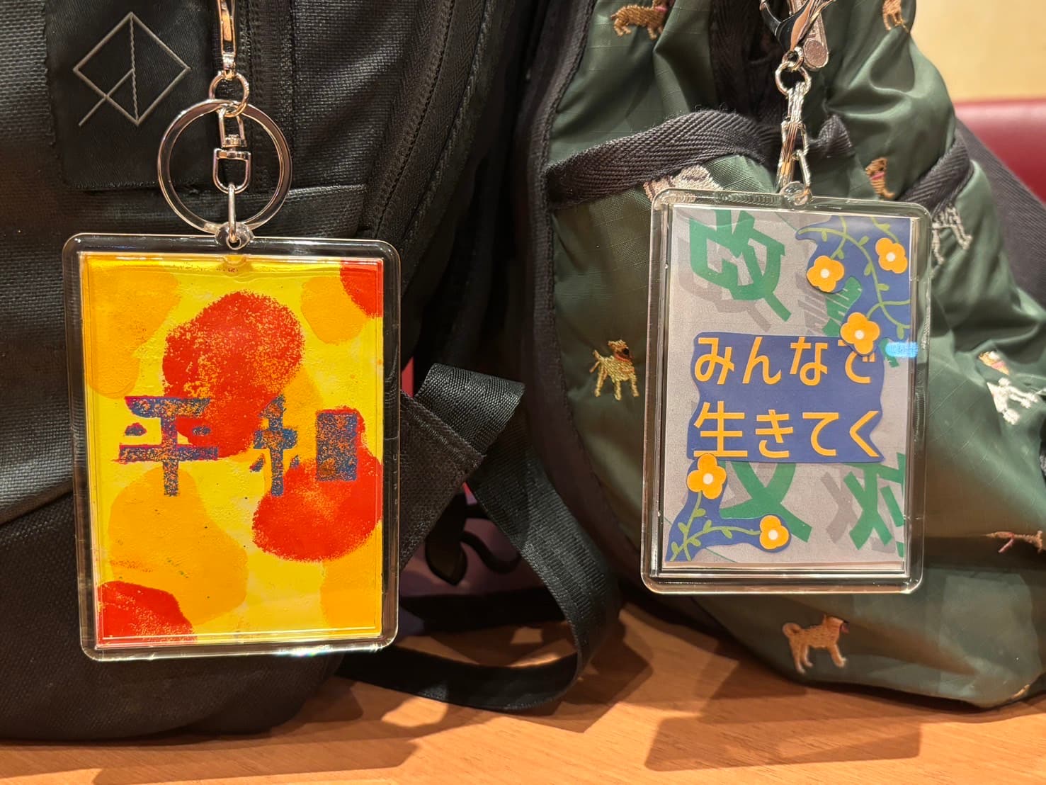鞄に下げられた『平和』『みんなで生きてく』のアクリルキーホルダー